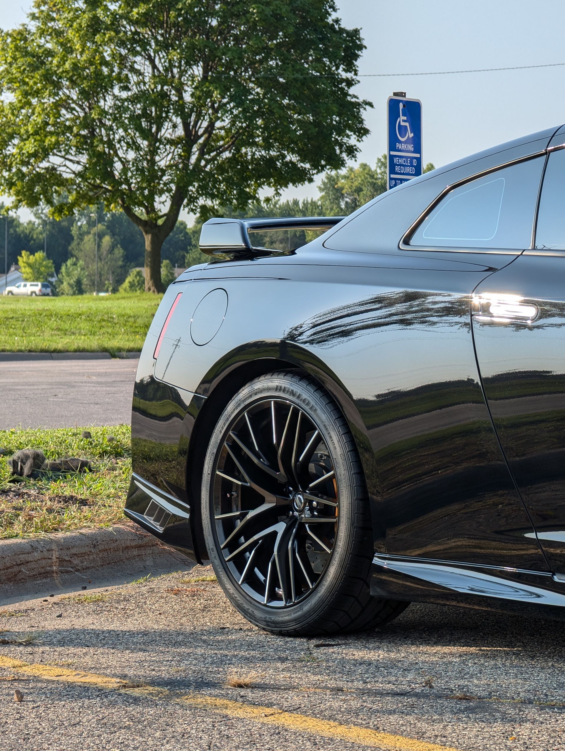 Cars in a dealership lot, mostly blue, red car in front, parked outdoors on pavement.