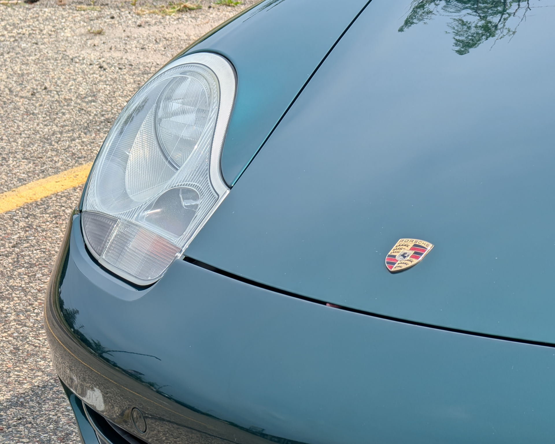 Green Porsche car with headlight and emblem.