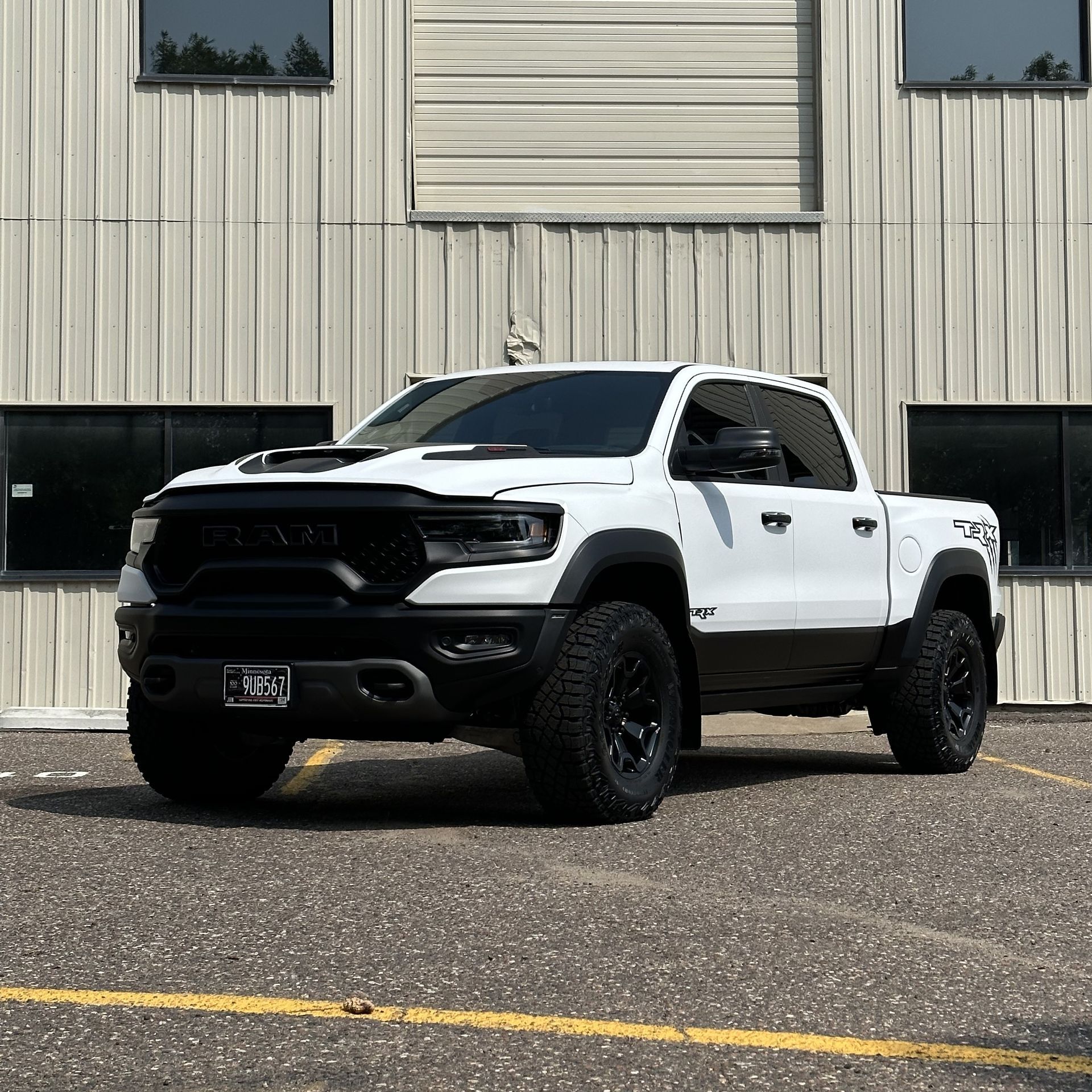 White Ram TRX truck parked in front of a metal building with black accents and black wheels.