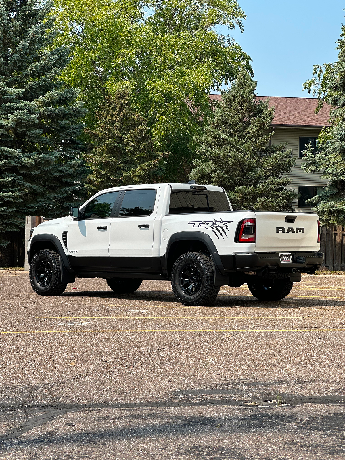 White Ram TRX truck parked on gravel, black tires, in front of trees and a building.