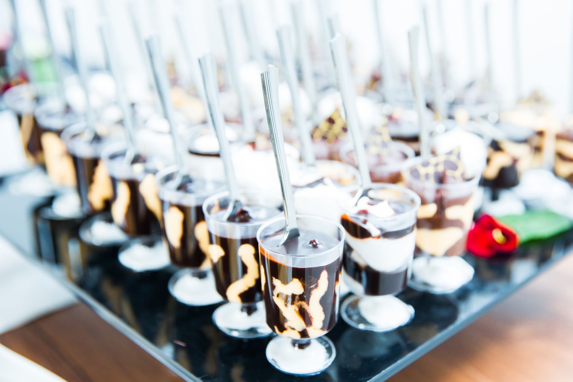 A tray of desserts with spoons in them on a table.