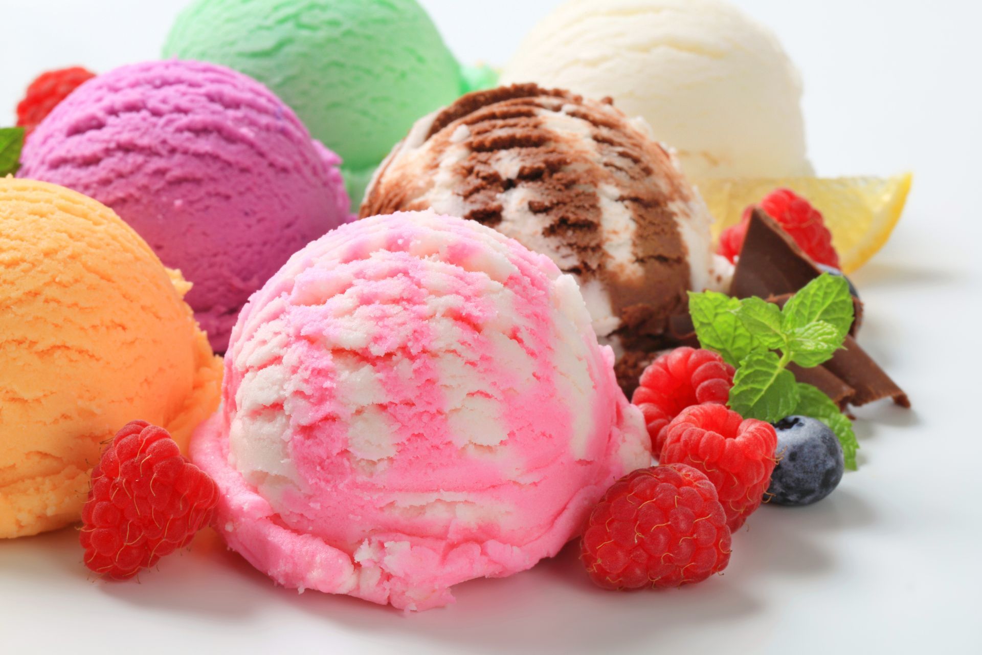 There are many different flavors of ice cream and berries on the table.