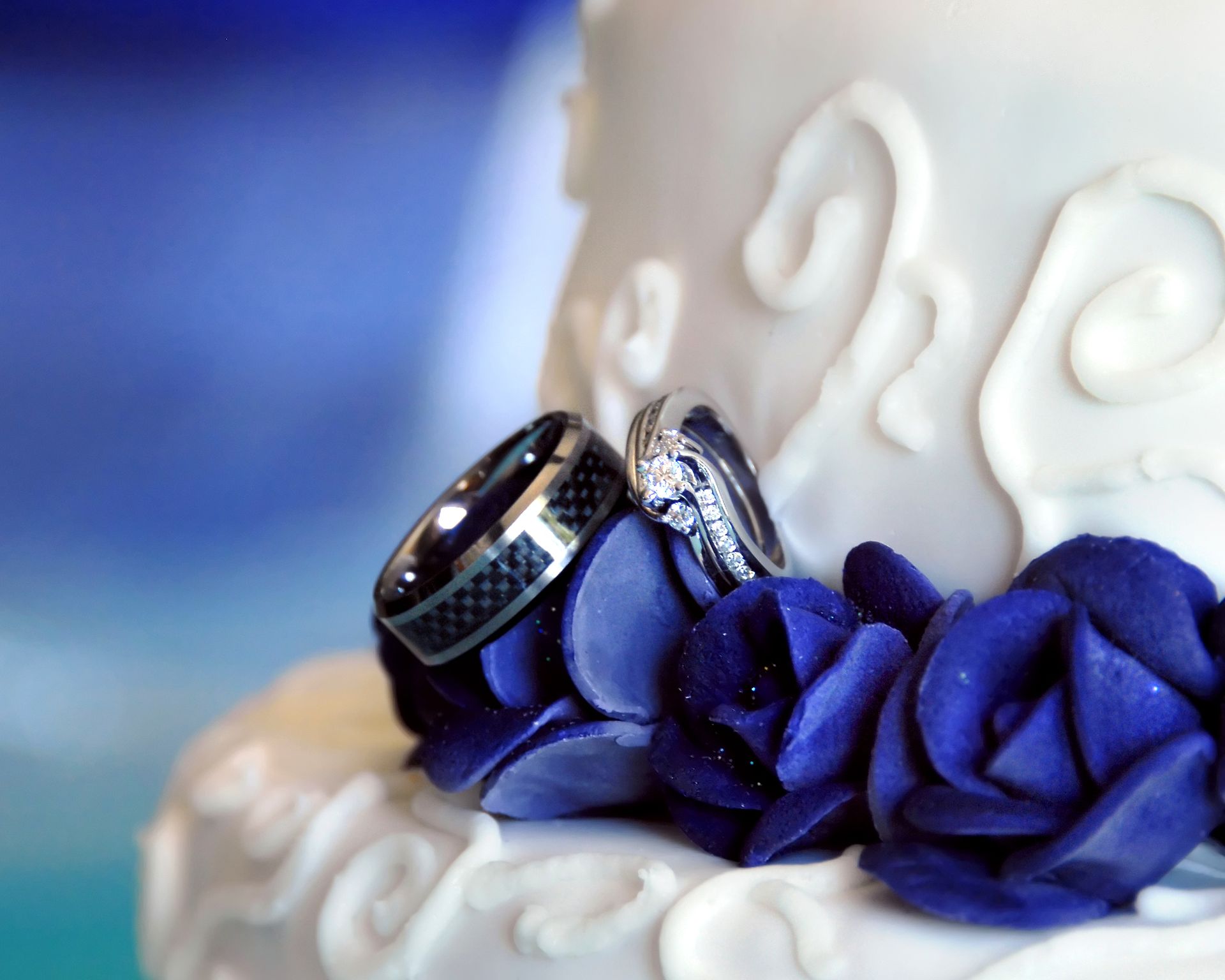 A couple of wedding rings sitting on top of a white cake