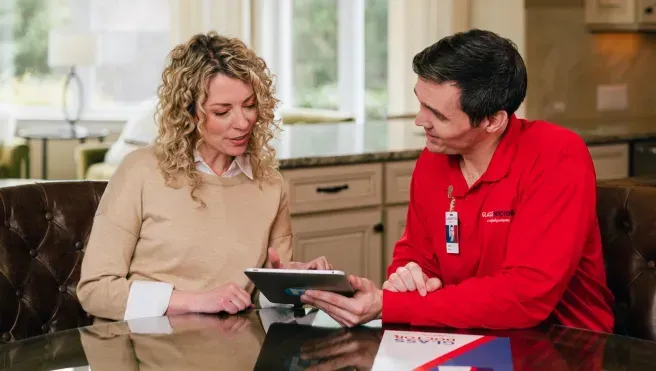 Woman and man in red uniform looking at a tablet, indoors.