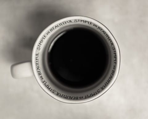 White mug with dark liquid inside,