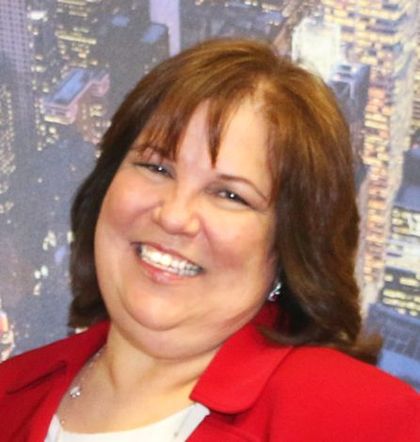 A woman in a red jacket smiles for the camera