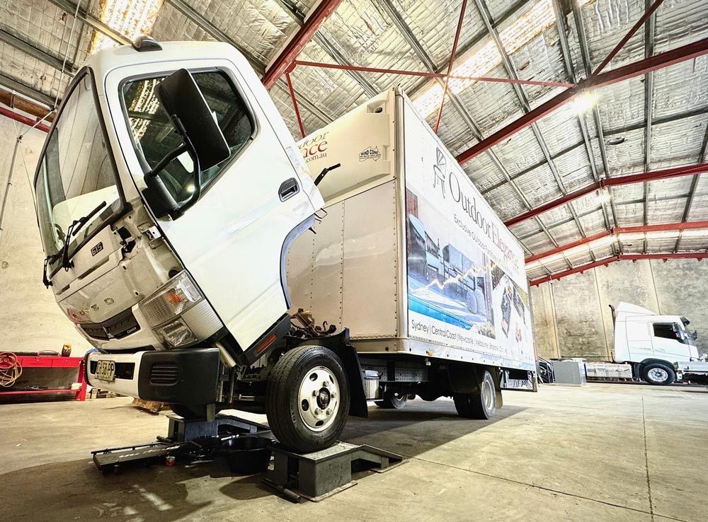 A White Truck Is Sitting on A Lift in A Garage — Inline Truck and Plant in Tuggerah, NSW
