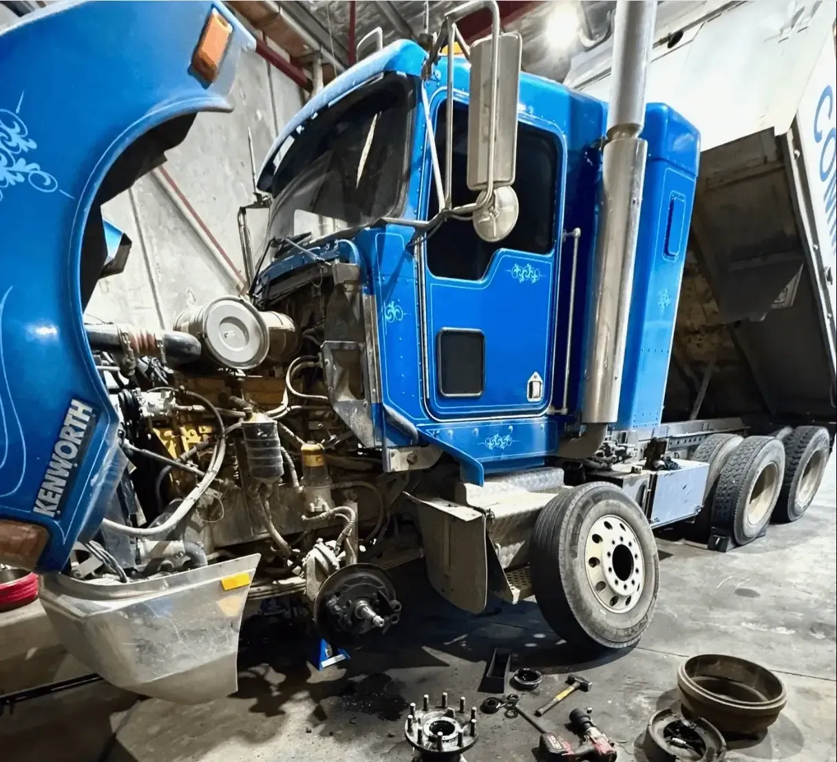 A blue kenworth truck is being worked on in a garage — Inline Truck and Plant in Tuggerah, NSW
