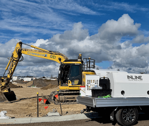 A yellow excavator is parked next to a white truck on a construction site — Inline Truck and Plant in Tuggerah, NSW