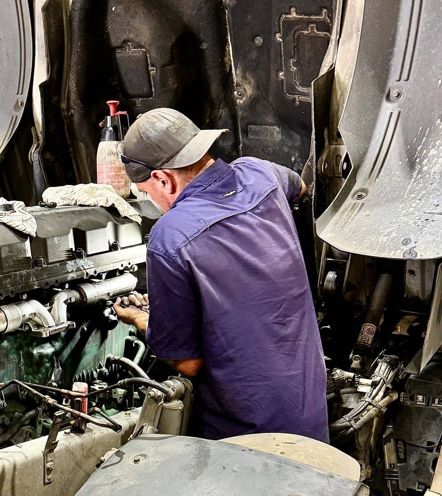 A Man in a Purple Shirt is Working on a Truck Engine — Inline Truck and Plant in Tuggerah, NSW