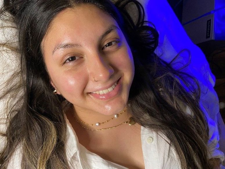 a woman is smiling while laying on a bed with a blue light behind her.