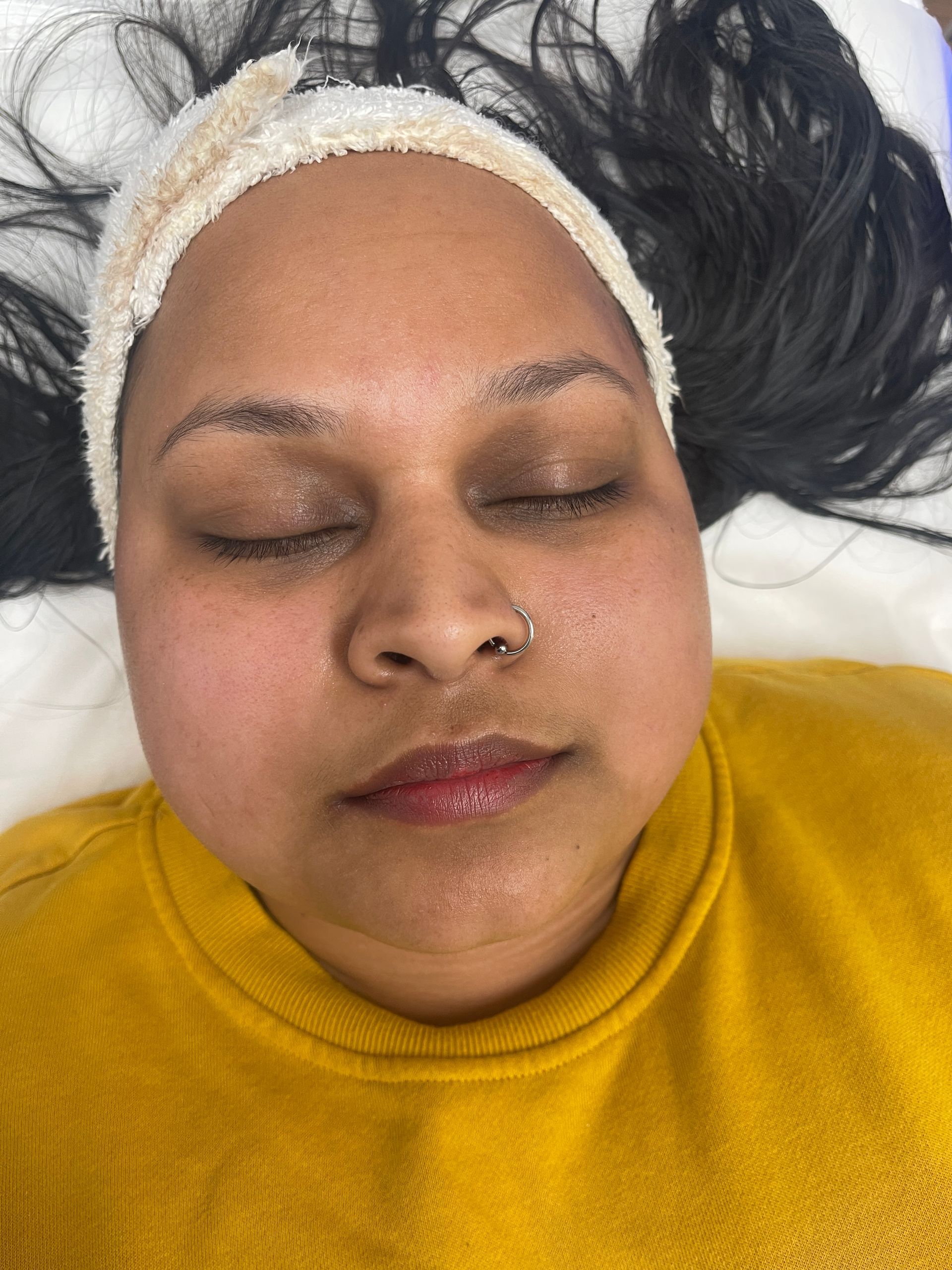 a woman with a nose ring is laying down with her eyes closed