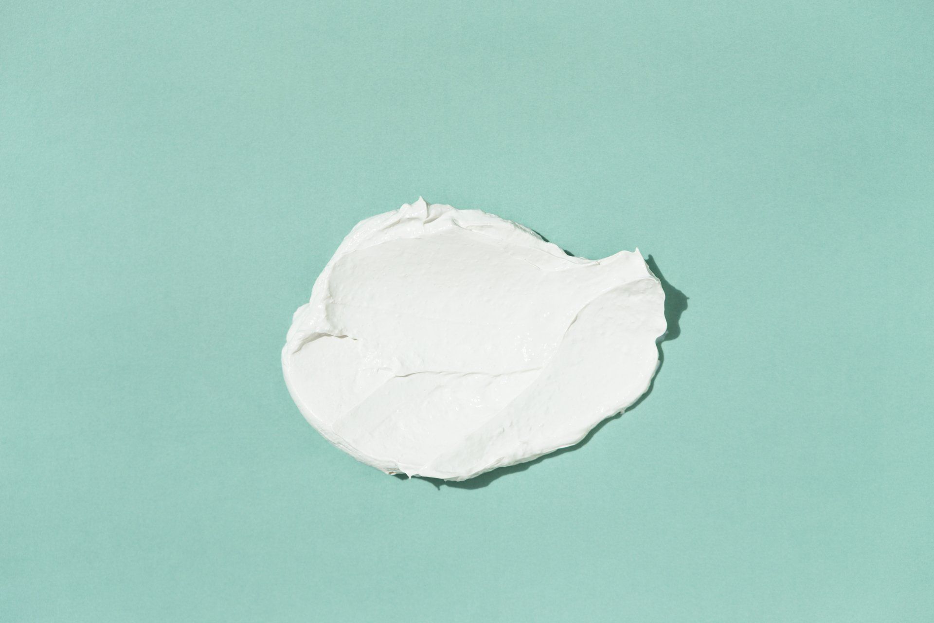 A swatch of white cream on a blue background.