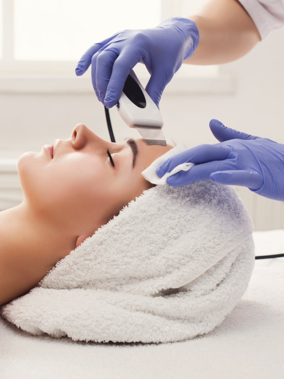 A woman with a towel wrapped around her head is getting a facial treatment.