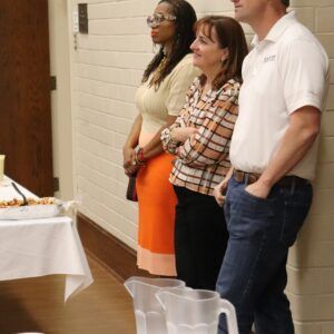 A group of people standing in front of a table with pitchers of water