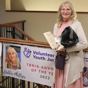 A woman is holding a sign that says volunteer youth jus