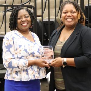 Two women are standing next to each other holding a trophy.