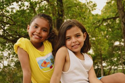 Two little girls are sitting next to each other and smiling for the camera.