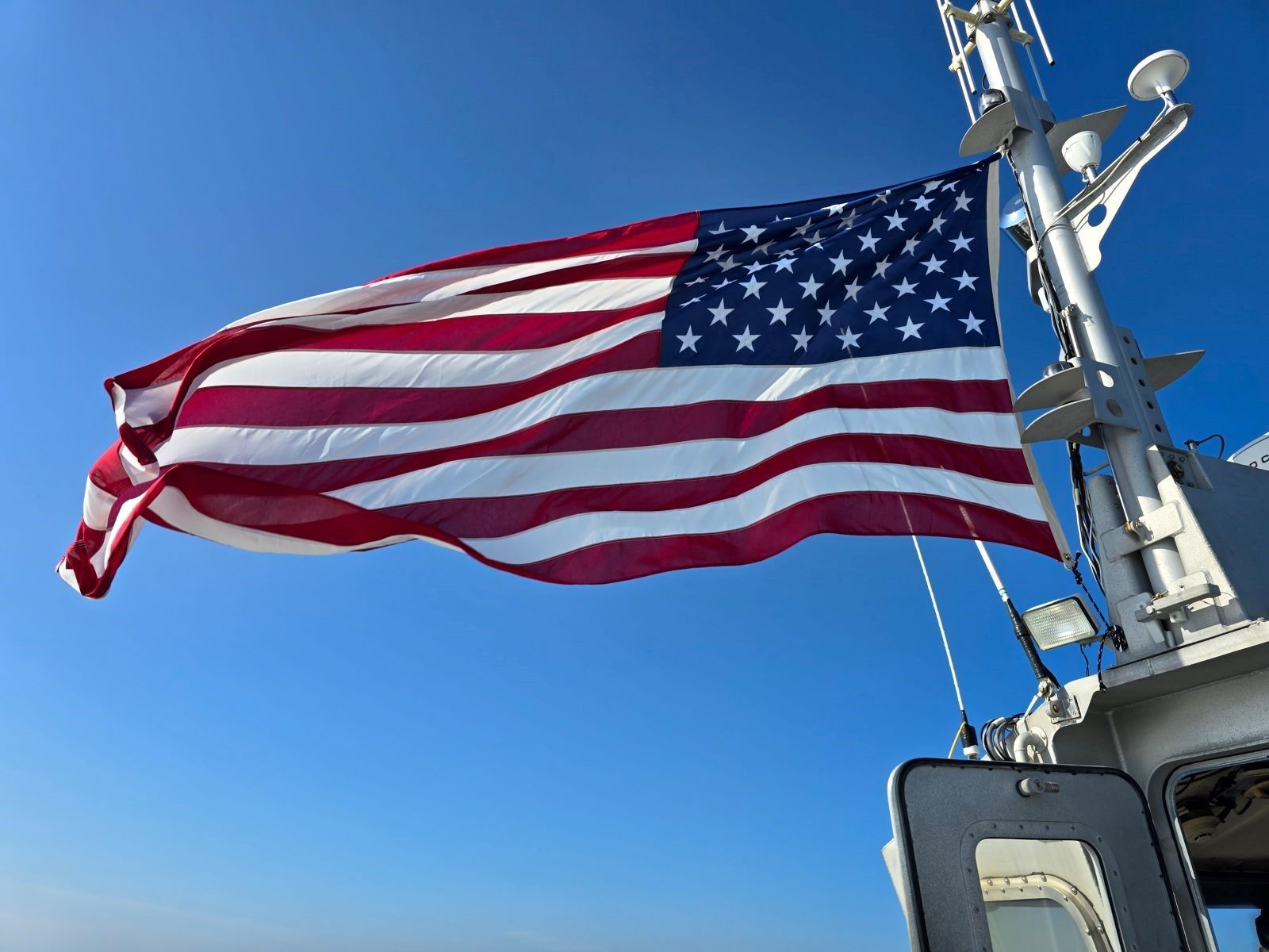 A large american flag is waving in the wind on a boat.