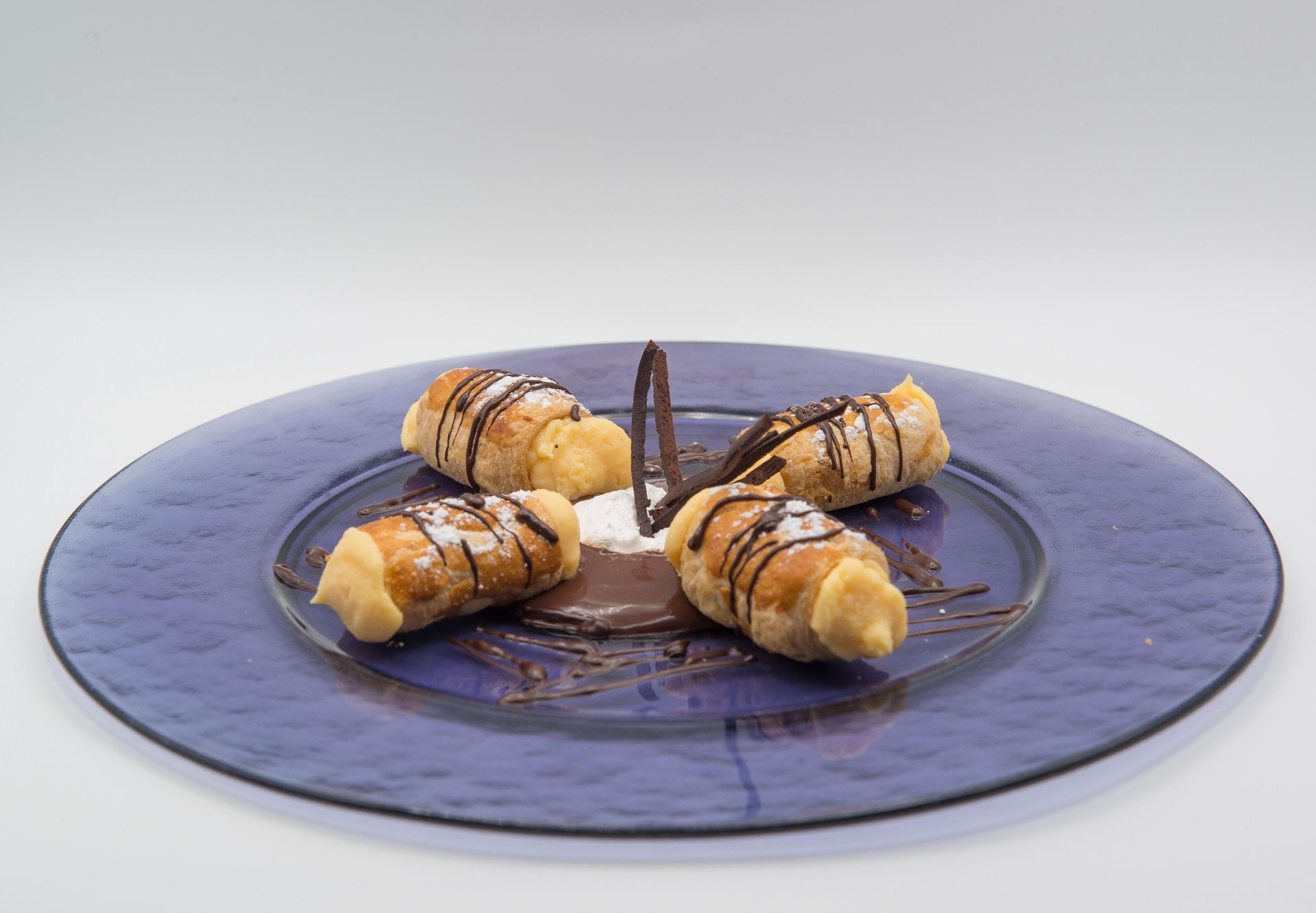 Cuatro croissants con salsa de chocolate en un plato azul