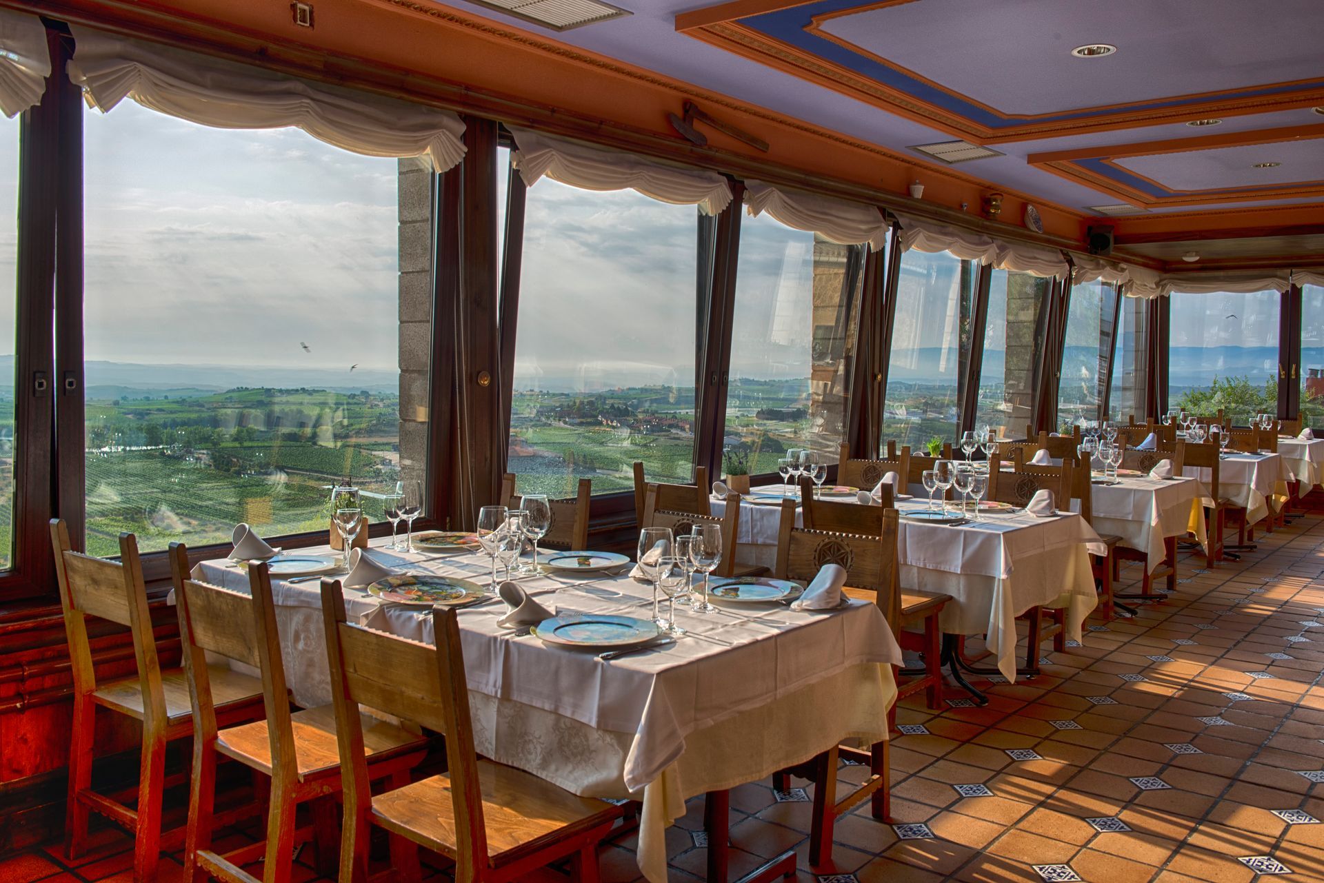 Un restaurante con mesas y sillas y vista a las montañas.