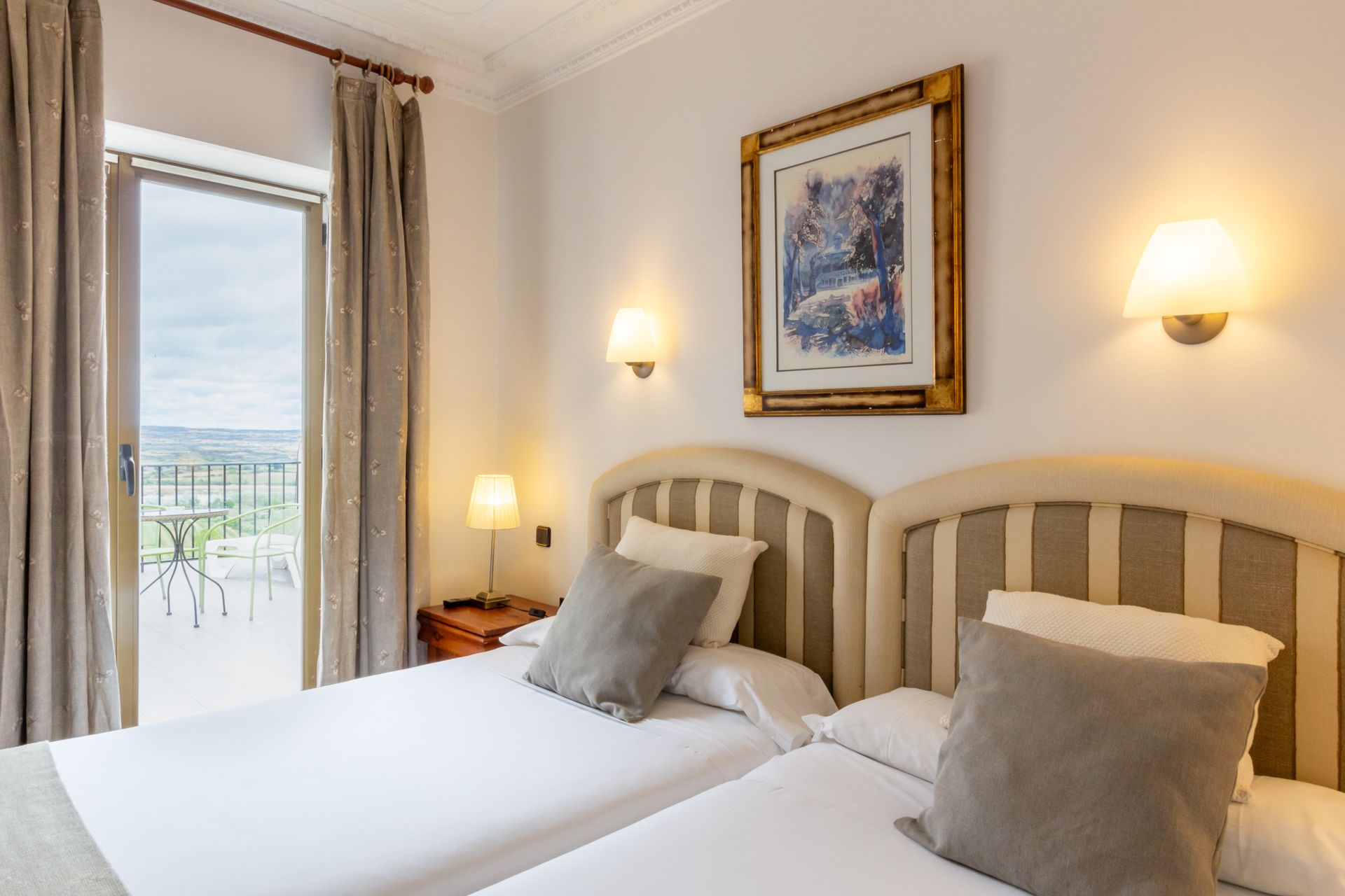 Un balcón con sillas de mimbre y una mesa con un gran edificio al fondo.