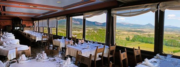 Un restaurante con mesas y sillas y vista a las montañas.