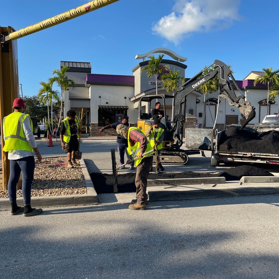Construction workers paving near a Taco Bell restaurant; sunny day.