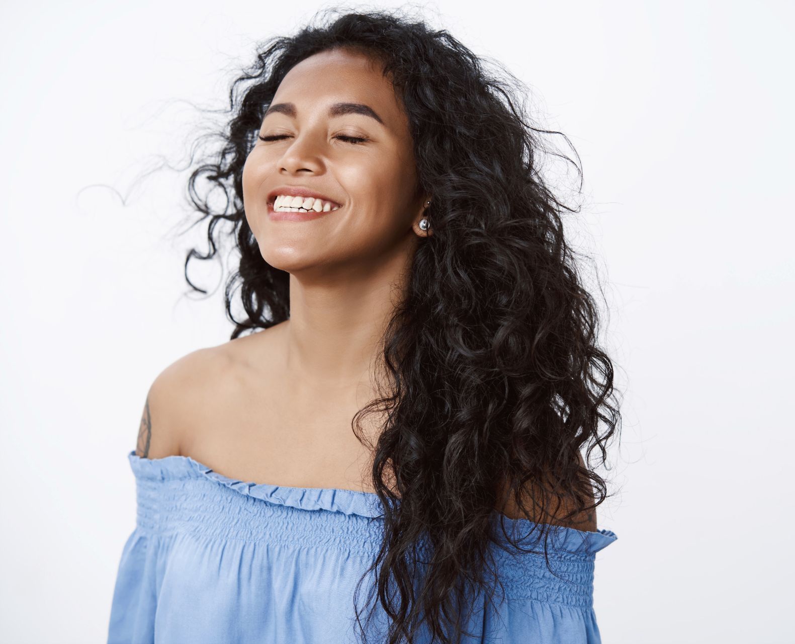 young woman with long wavy hair and blue off-the-shoulder blouse