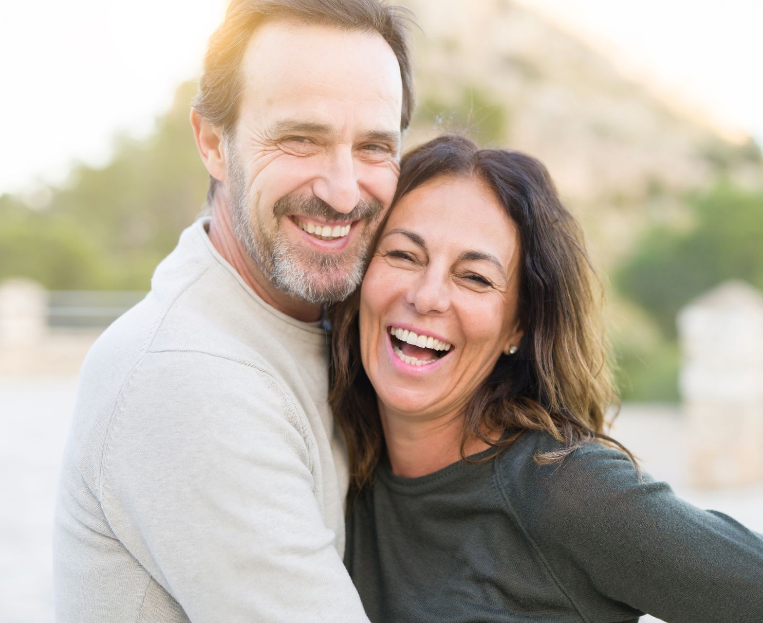 mature couple holding each other and smiling with mountain in the background