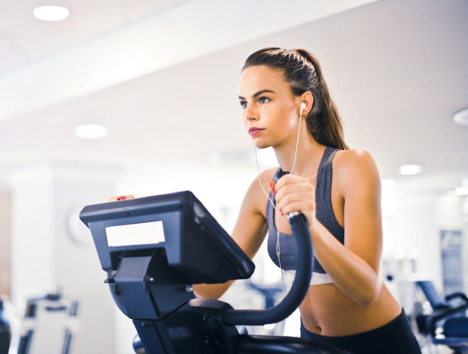 young white woman exercising on elliptical machine in gym