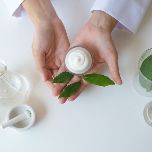 A Person Is Holding A Jar Of Cream With Green Leaves In Their Hands – Terrigal, NSW - Anjule Beauty Therapy