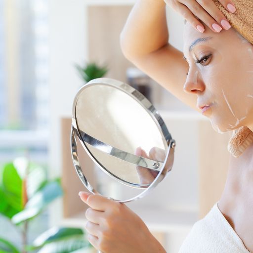 A Woman Is Looking At Her Face In A Mirror – Terrigal, NSW - Anjule Beauty Therapy