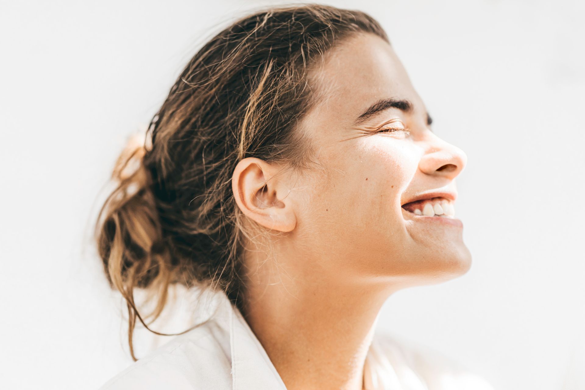 A Woman Is Smiling With Her Eyes Closed And Her Hair In A Bun – Terrigal, NSW - Anjule Beauty Therapy