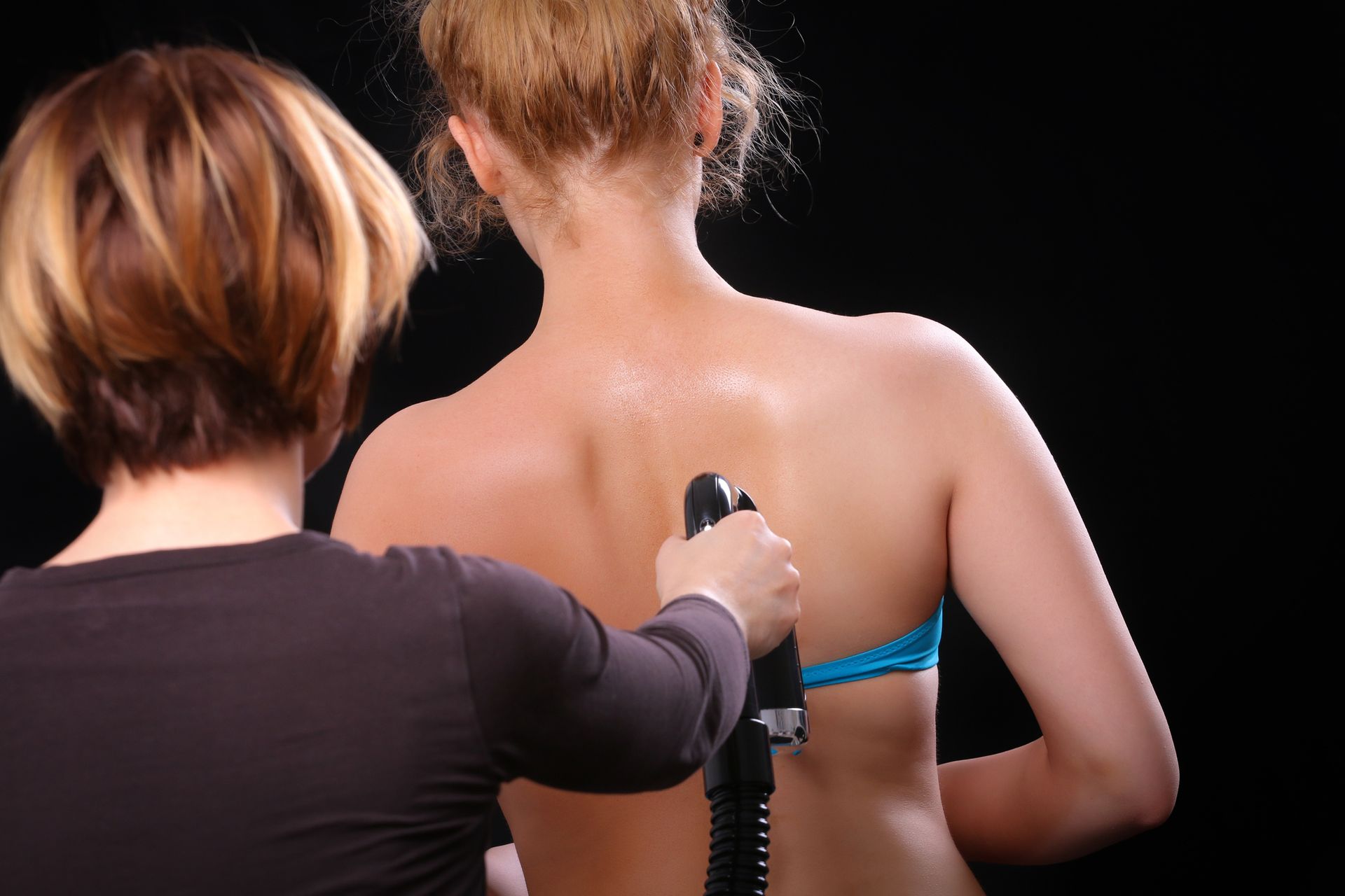 One Woman Is Applying Tan Spray To The Back Of Another Woman – Terrigal, NSW - Anjule Beauty Therapy