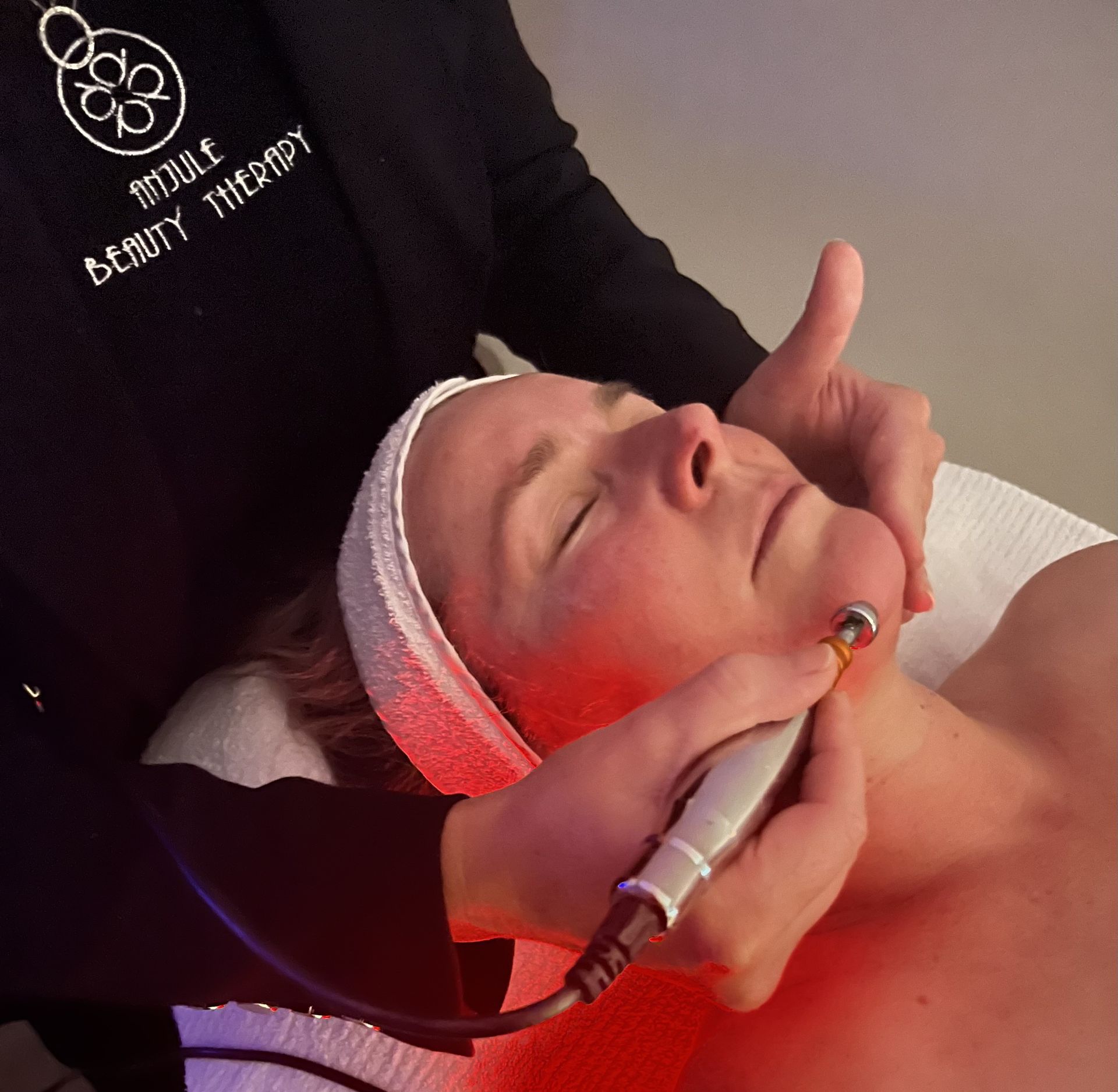 A Woman Is Smiling While Looking At Her Face In A Mirror – Terrigal, NSW - Anjule Beauty Therapy