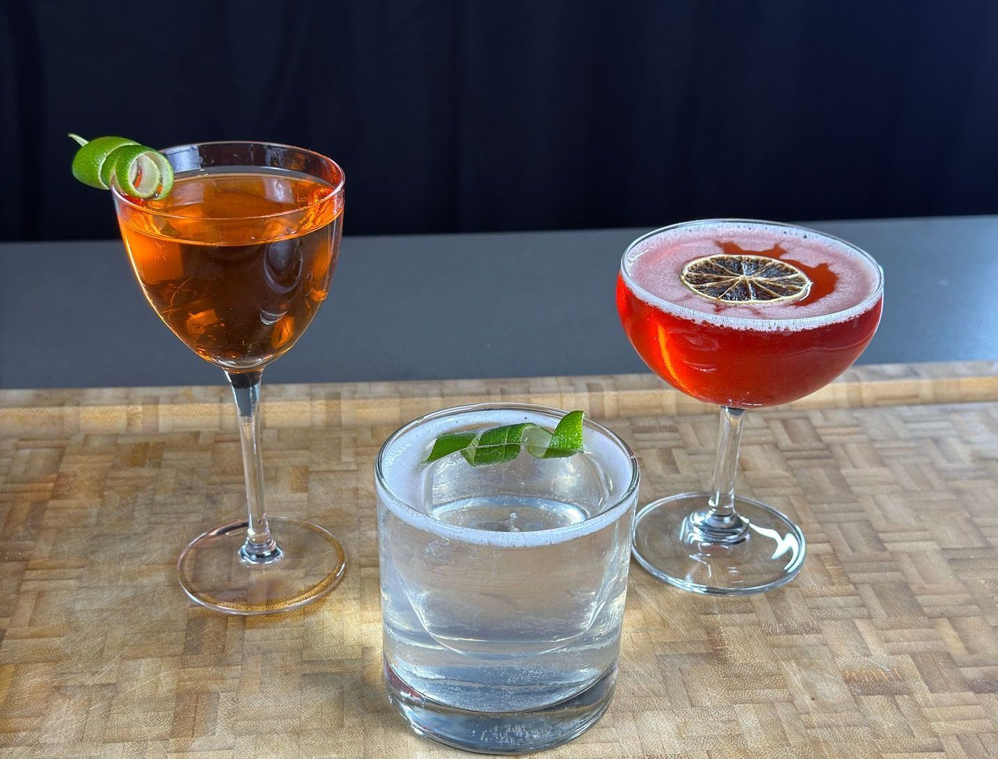 Three different types of cocktails are sitting on a wooden table.