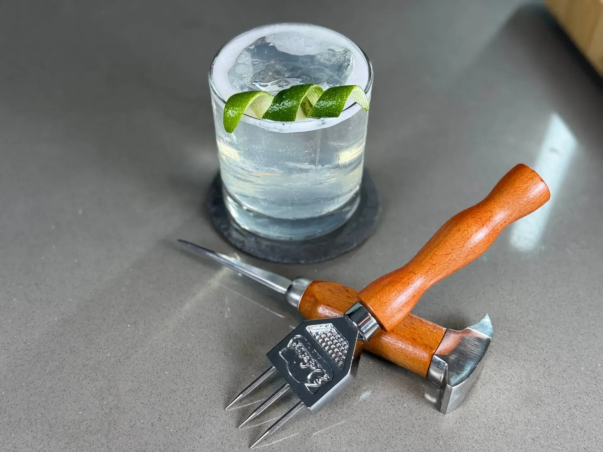 A glass of gin and tonic next to a pair of ice picks