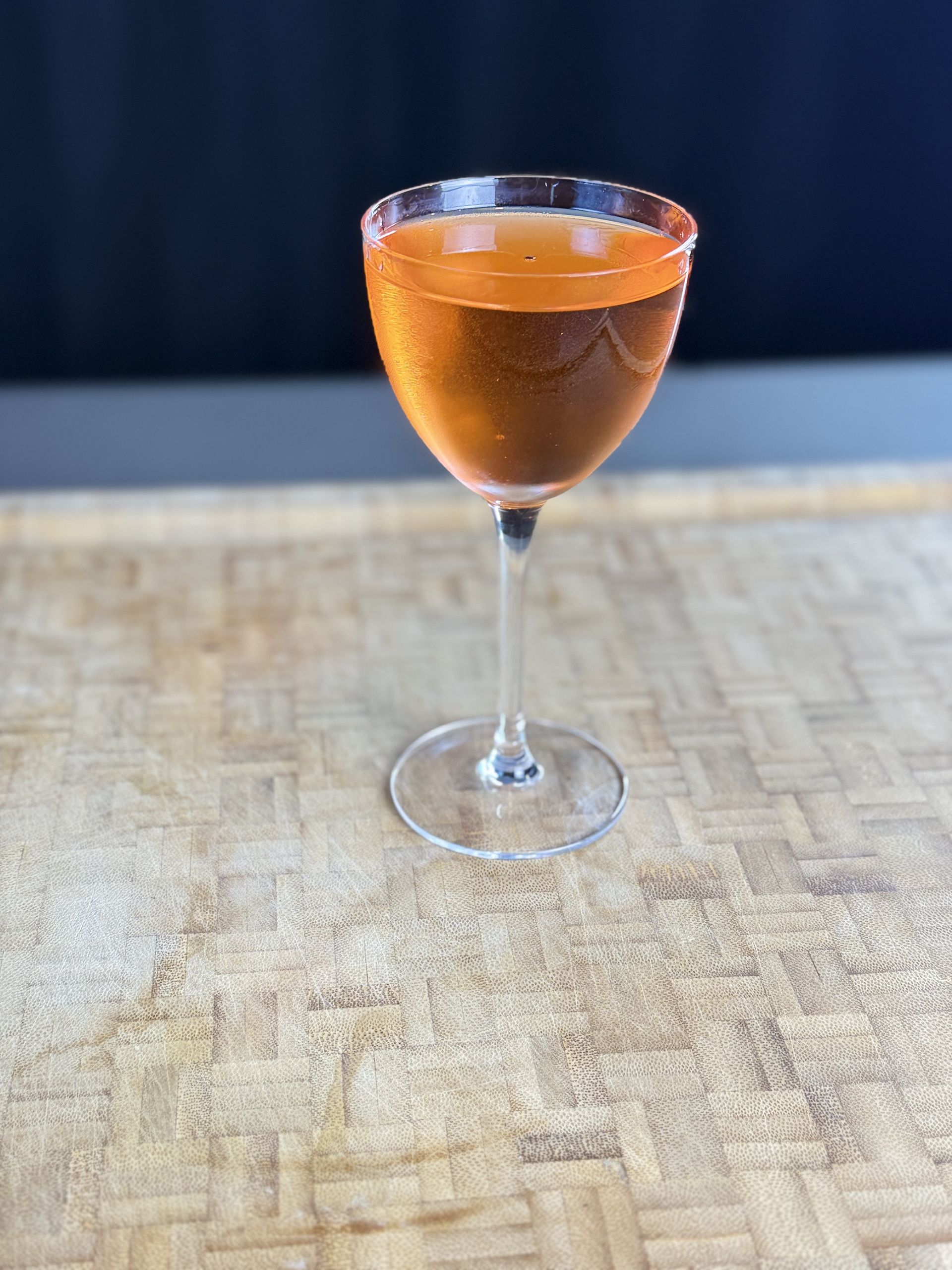 A glass of orange liquid is sitting on a wooden table.