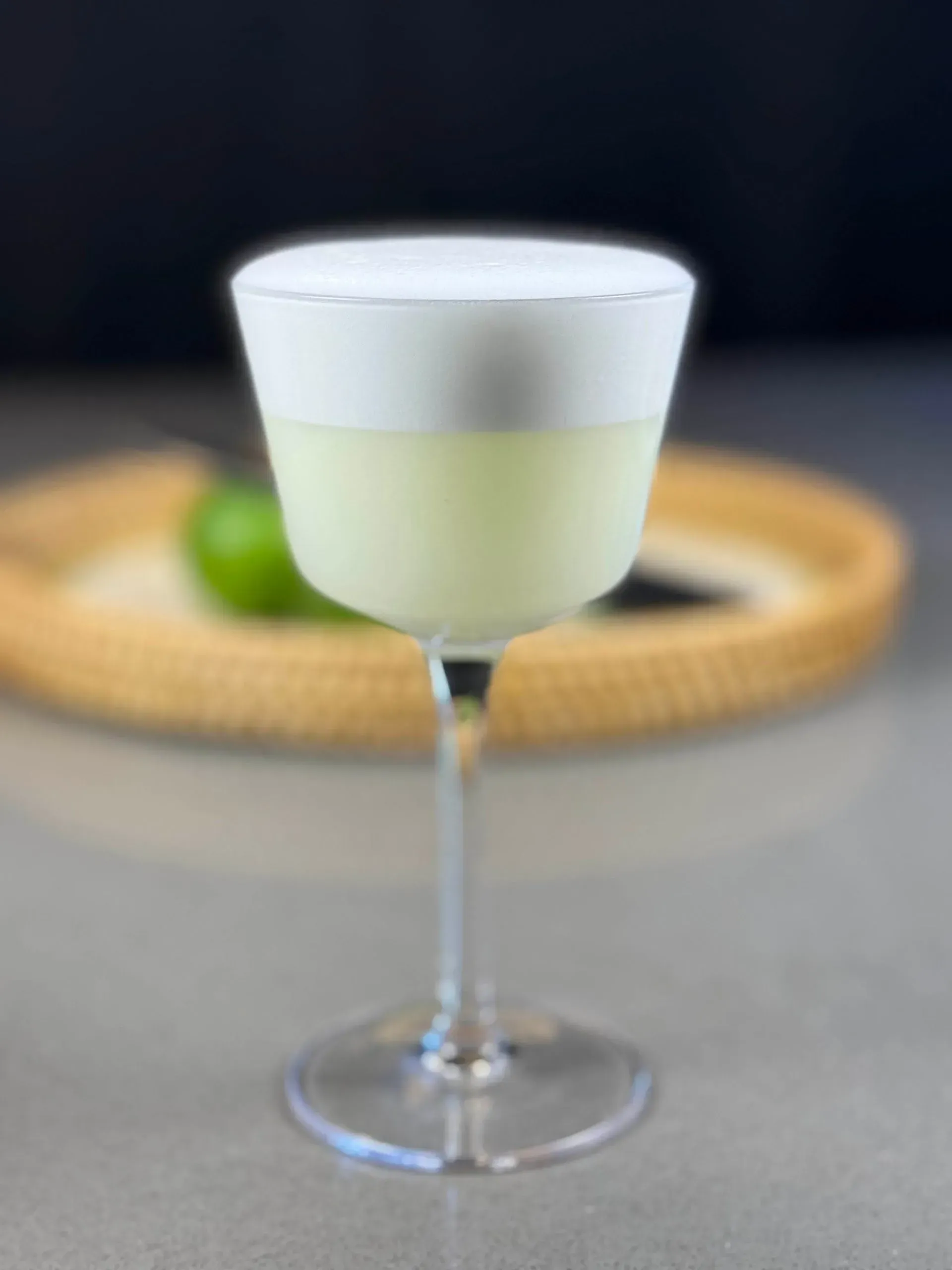 A close up of a cocktail in a wine glass on a table.