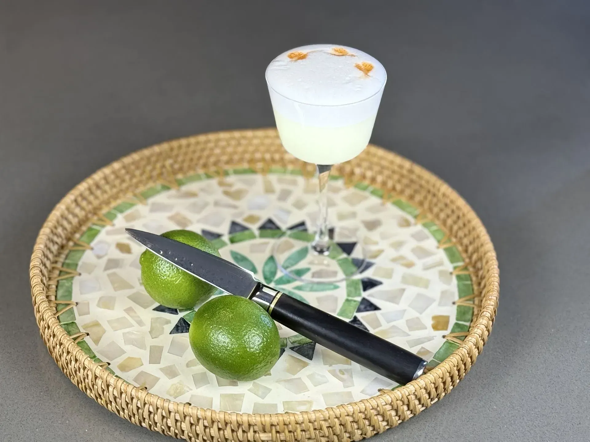 A tray with limes and a drink on it