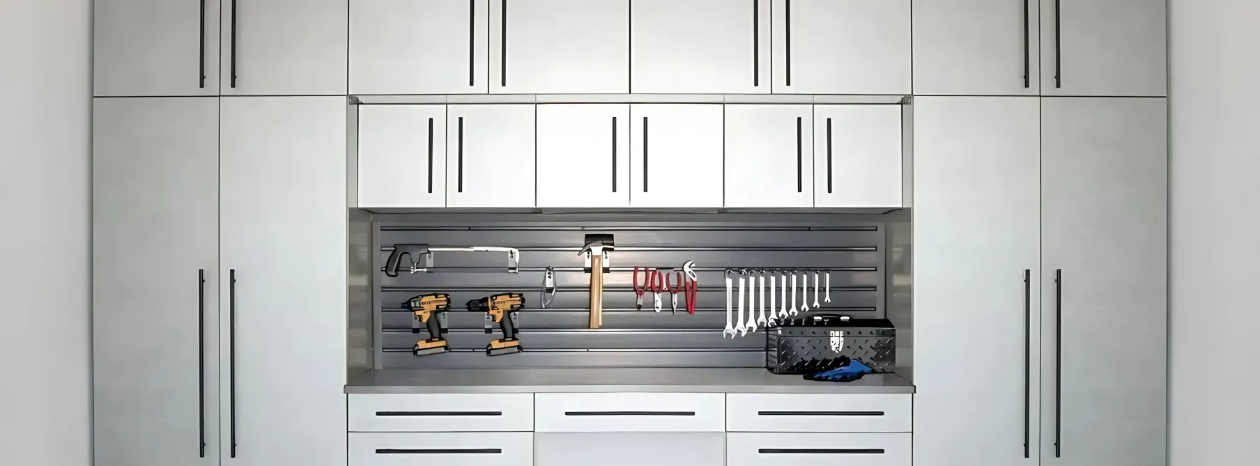 A kitchen with white cabinets , drawers , and a shelf with tools on it.