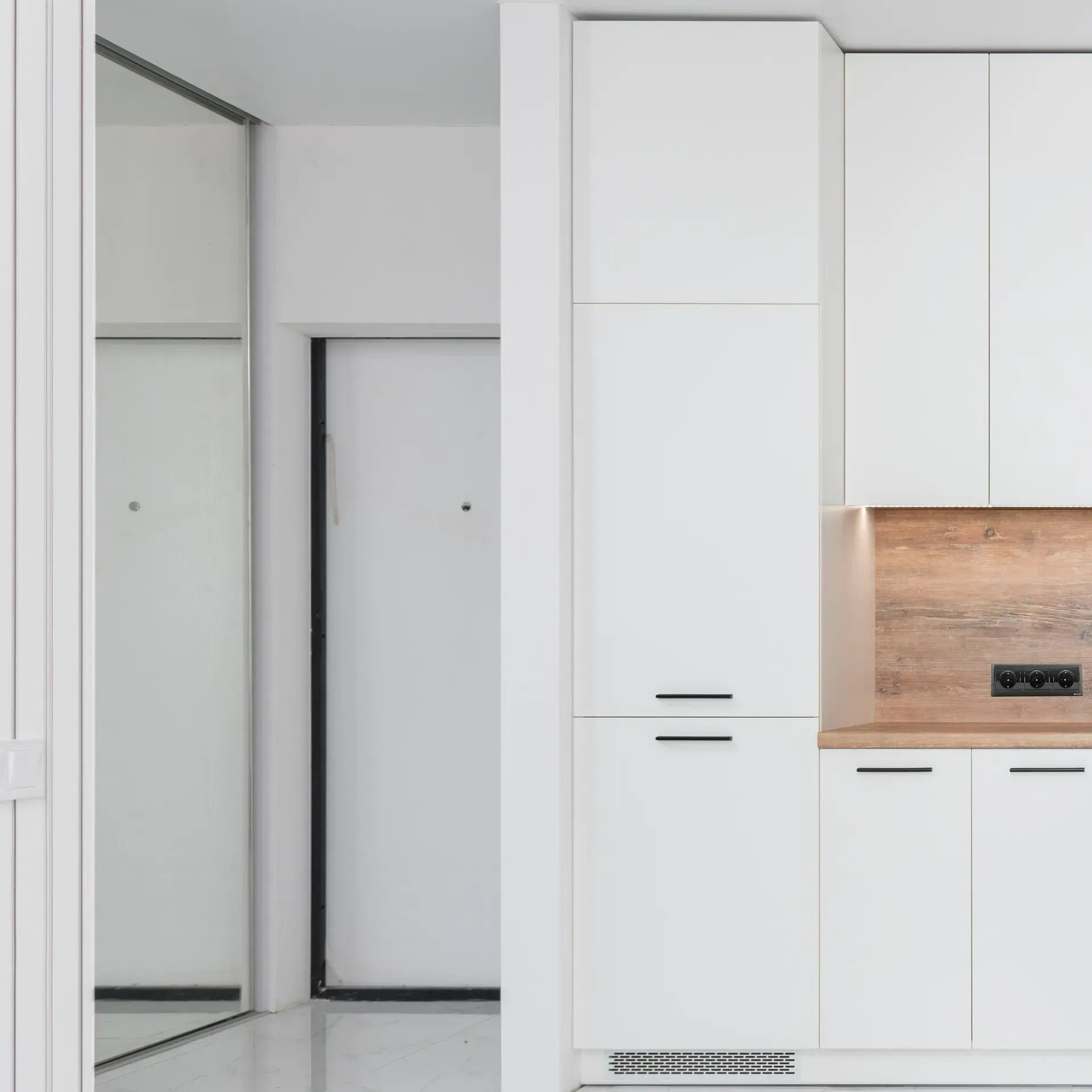 A kitchen with white cabinets and a wooden counter top.