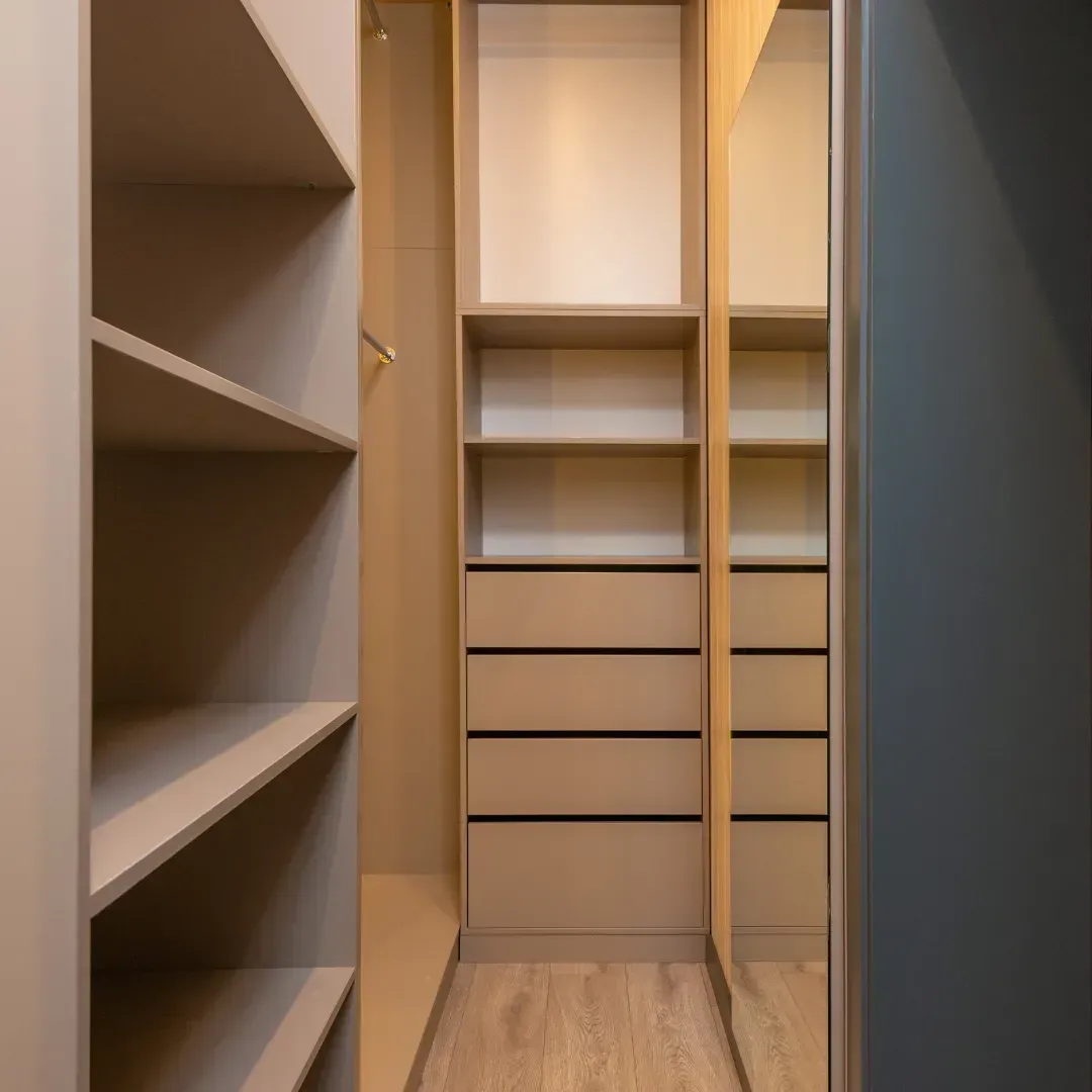 A walk in closet with shelves , drawers and a mirror.