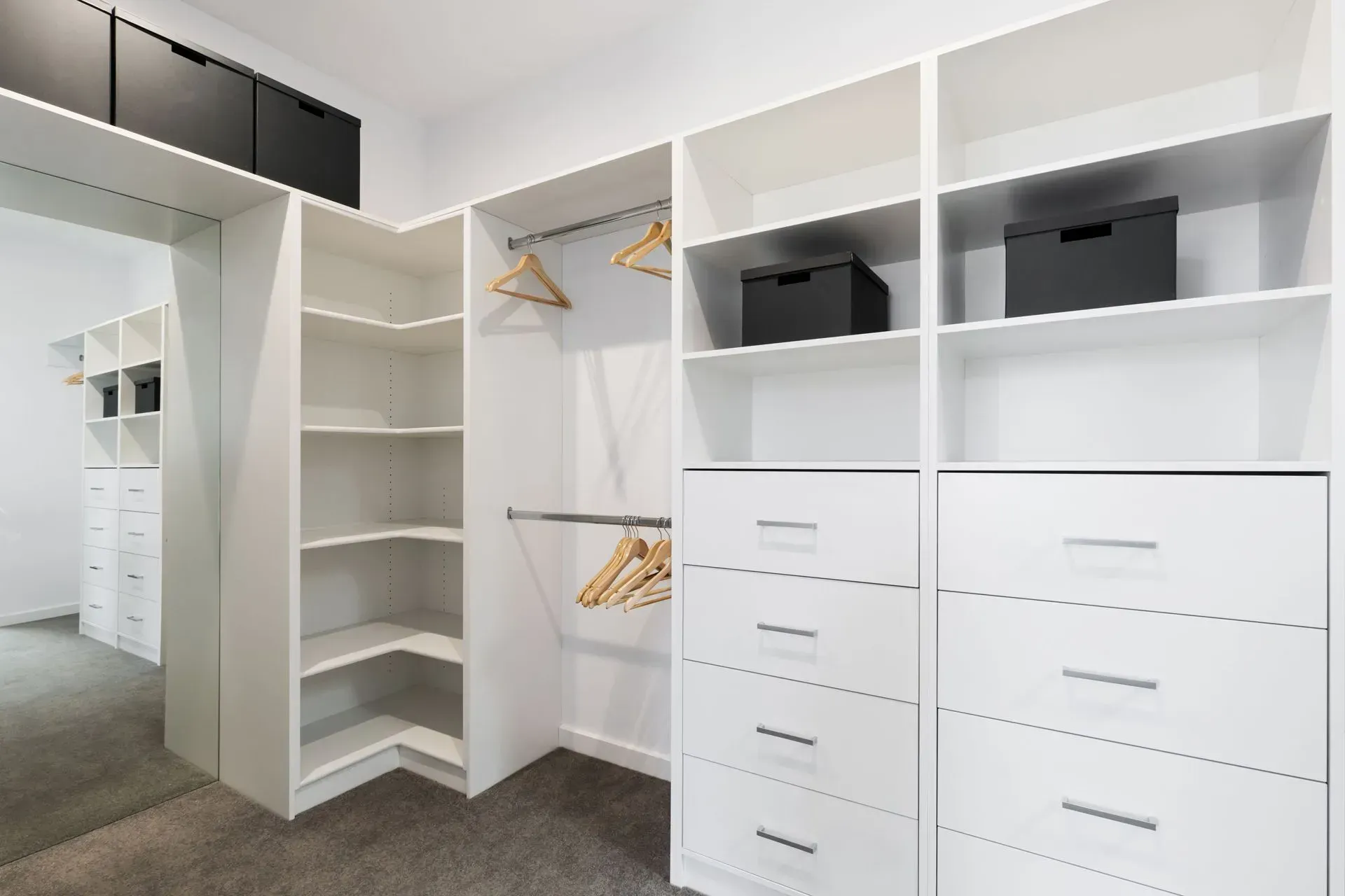 A walk in closet with lots of shelves , drawers , and a mirror.