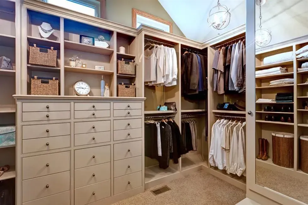 A walk in closet with lots of clothes and drawers