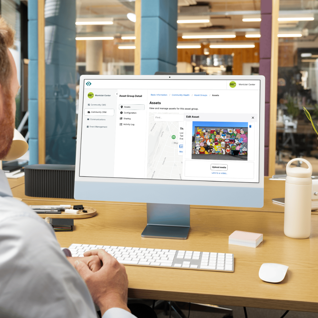 A person works at a desk on a laptop displaying a digital project management dashboard in a bright, modern office.