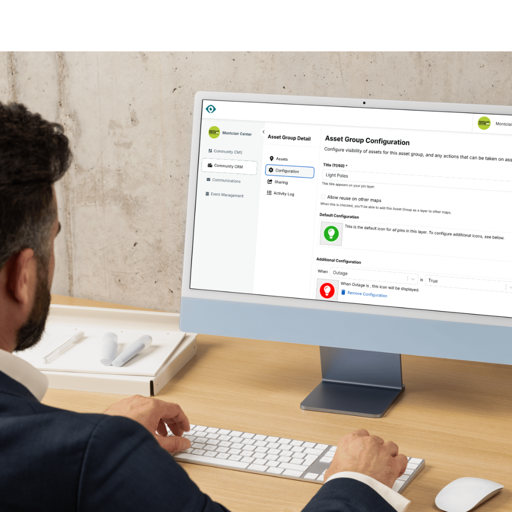 Two people sit on adjacent couches in a brightly lit office, working together on a laptop placed on a small wooden table.