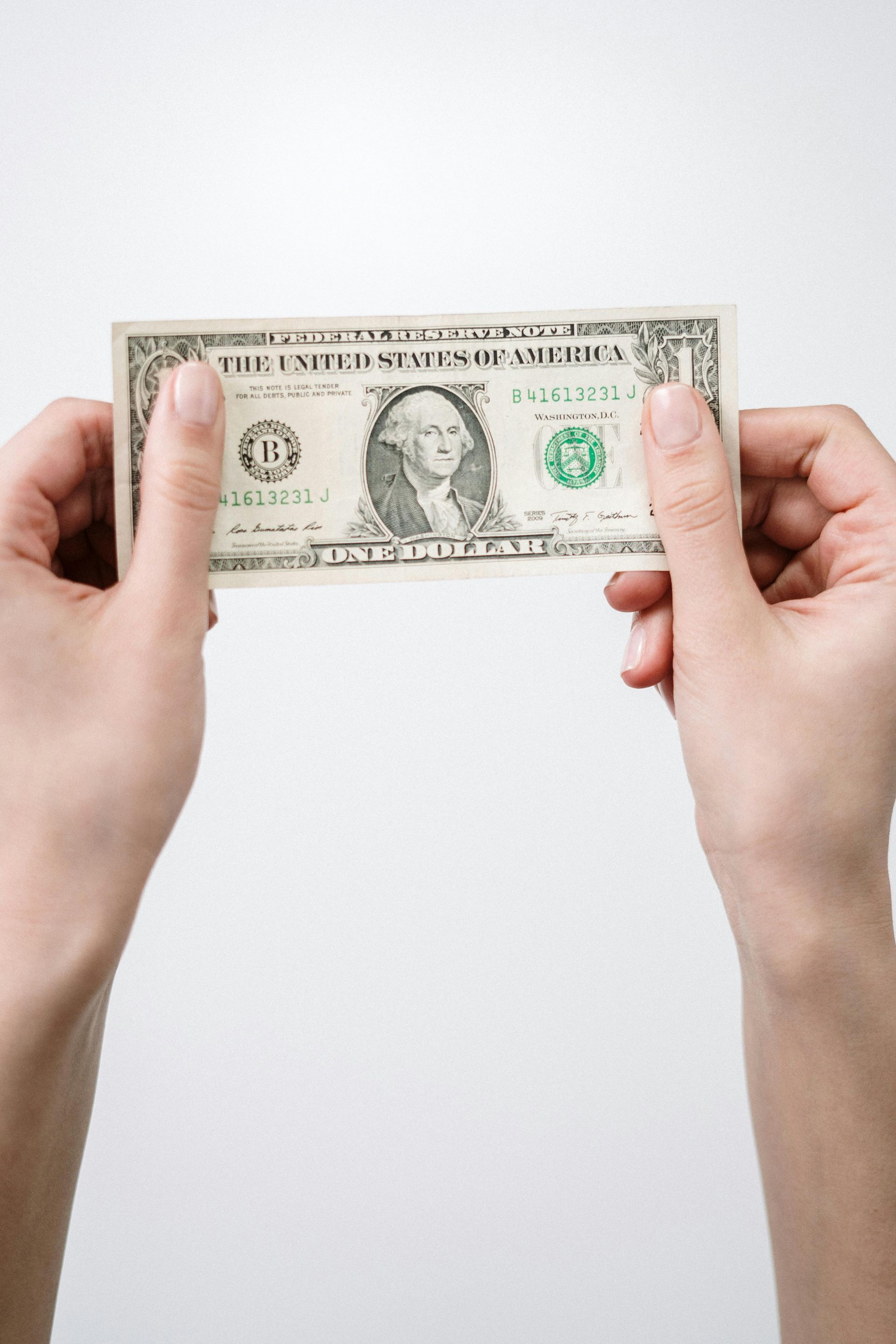A person is holding a one dollar bill in their hands