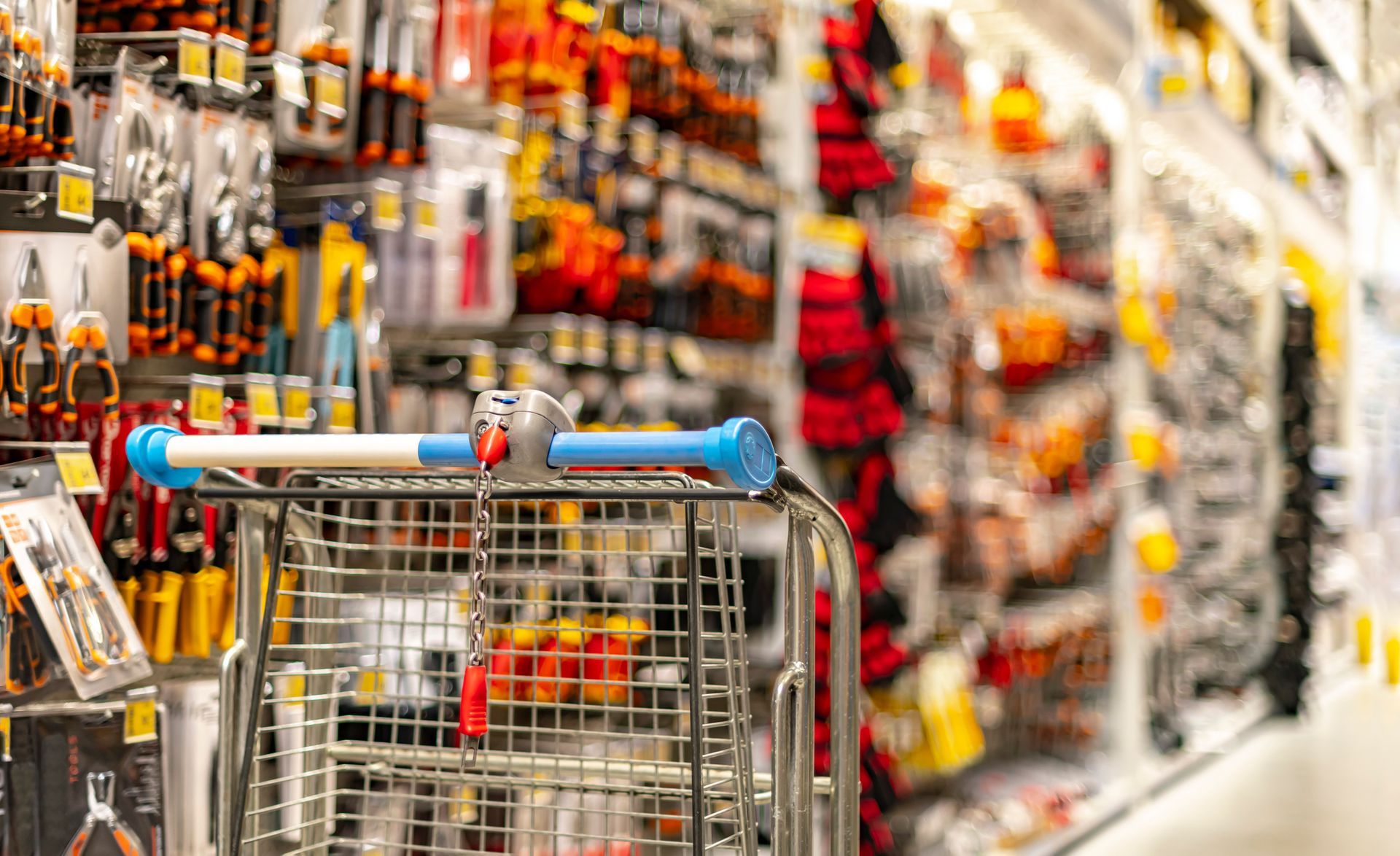 A shopping cart is being pushed down a aisle in a hardware store.